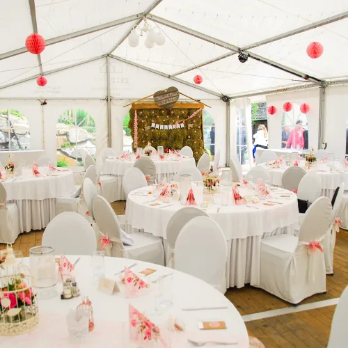 Hochzeit im Zelt - Zelt von innen mit runden Tischen und Sesseln. Rosa geschmückt